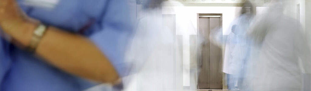 blurred figures of doctors and nurses in a hospital corridor